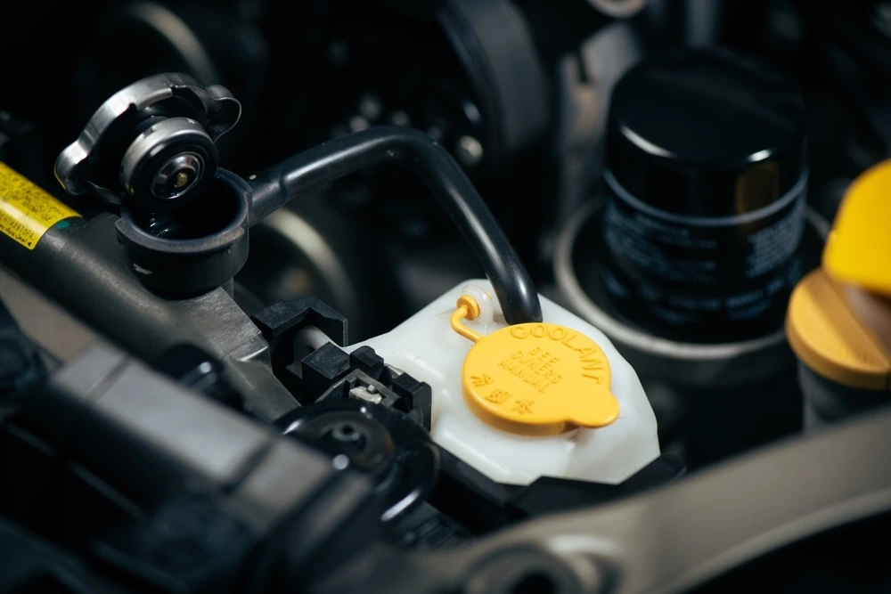 Open fluid reservoirs and yellow caps in a vehicle engine bay